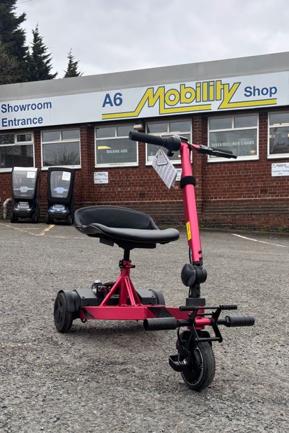 Lightweight pink portable mobility scooter pictured in the car park of A6 Mobility Shop in Stockport, Greater Manchester