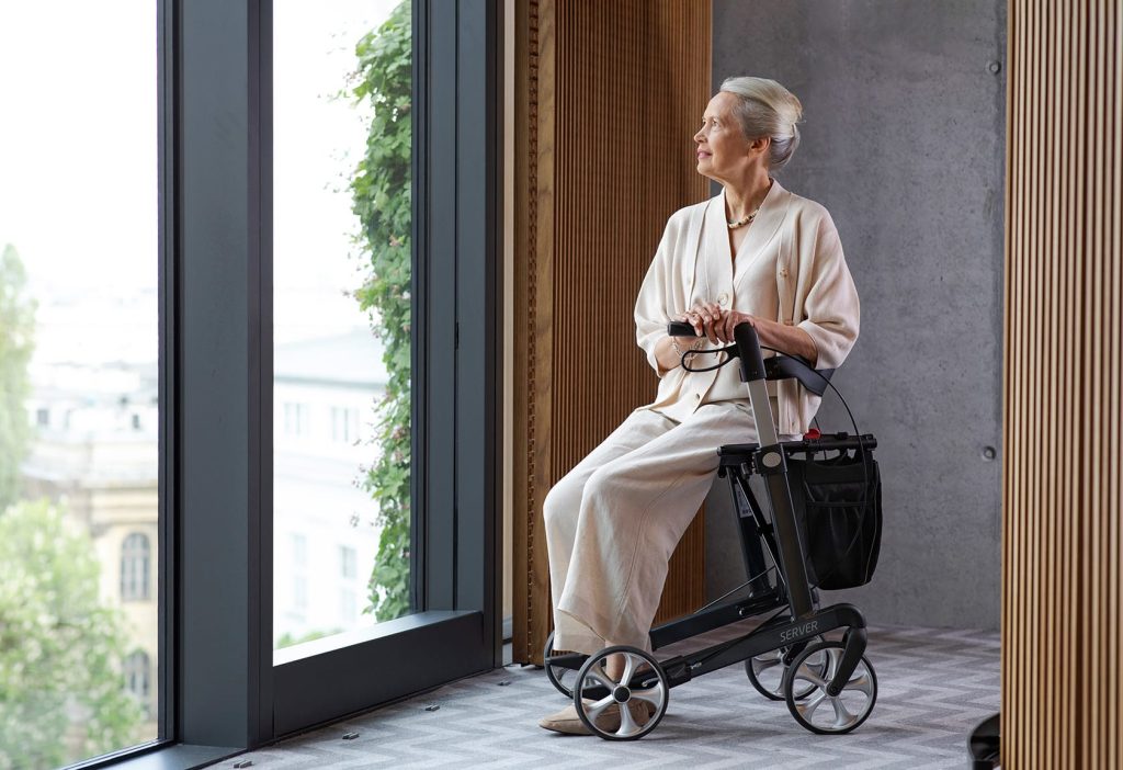Woman sat on 4 wheel rollator walking aid