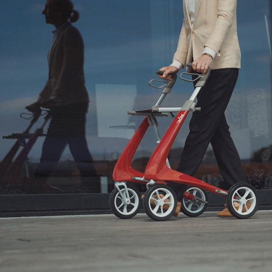 Red 4 wheel rollator walking aid with seat and handles